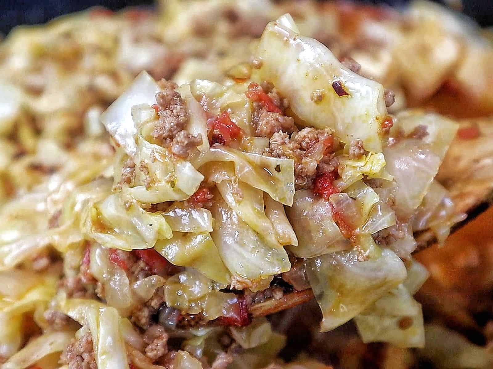 Ground beef and chopped cabbage cooked together in a cast-iron skillet with diced tomatoes, onions, garlic, and seasonings, finished with red pepper flakes for an easy one-pan dinner.