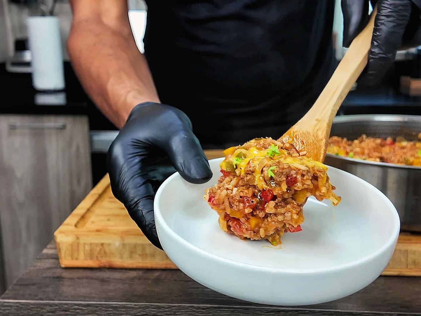 Cheesy unstuffed bell pepper skillet made with seasoned ground beef, white rice, red, yellow and green bell peppers, tomatoes and melted cheddar cheese, garnished with fresh parsley.