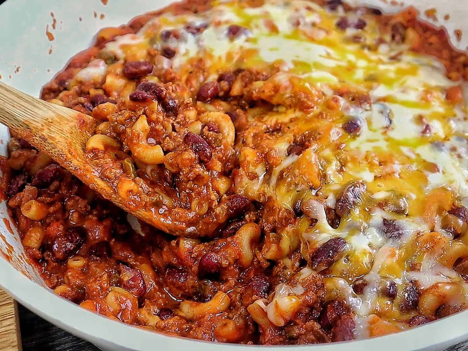 cheesy homemade chili mac made with elbow macaroni, seasoned ground beef, kidney beans, rich tomato sauce, and melted cheddar, Monterey Jack, and mozzarella cheese.