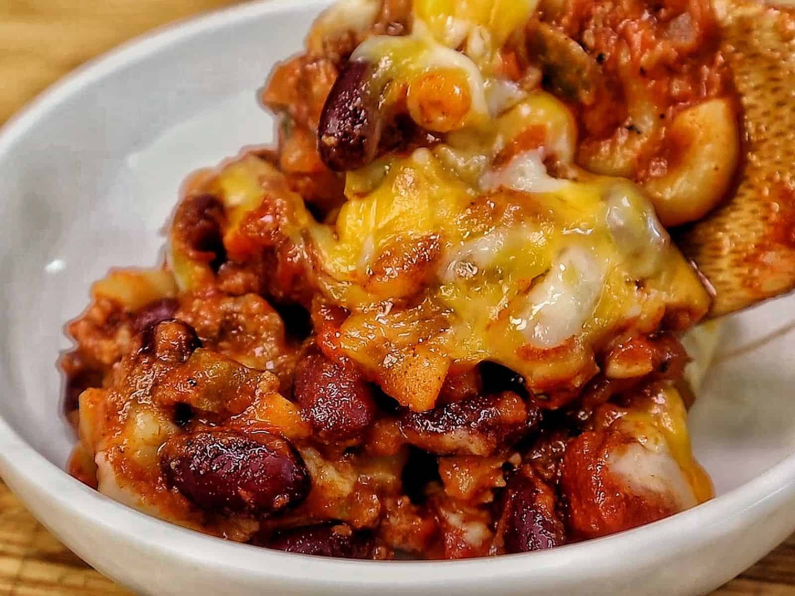 cheesy homemade chili mac made with elbow macaroni, seasoned ground beef, kidney beans, rich tomato sauce, and melted cheddar, Monterey Jack, and mozzarella cheese.