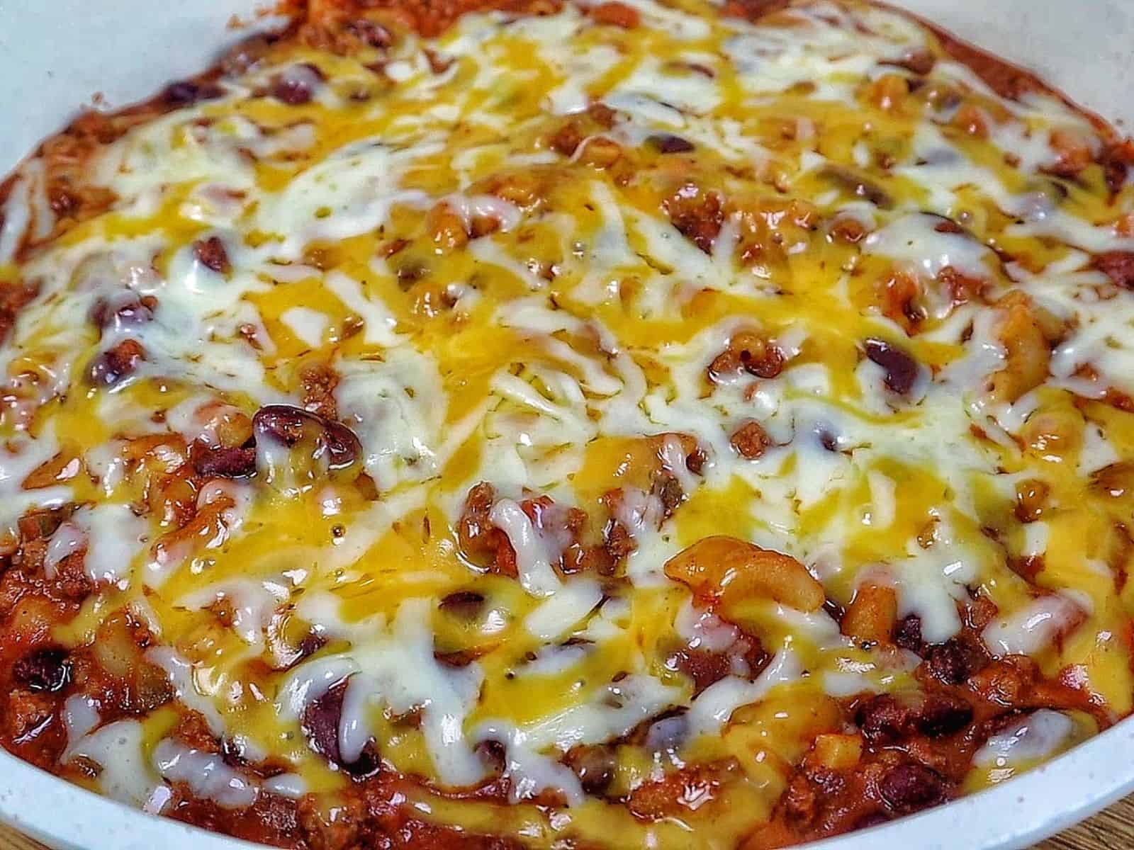 cheesy homemade chili mac made with elbow macaroni, seasoned ground beef, kidney beans, rich tomato sauce, and melted cheddar, Monterey Jack, and mozzarella cheese.