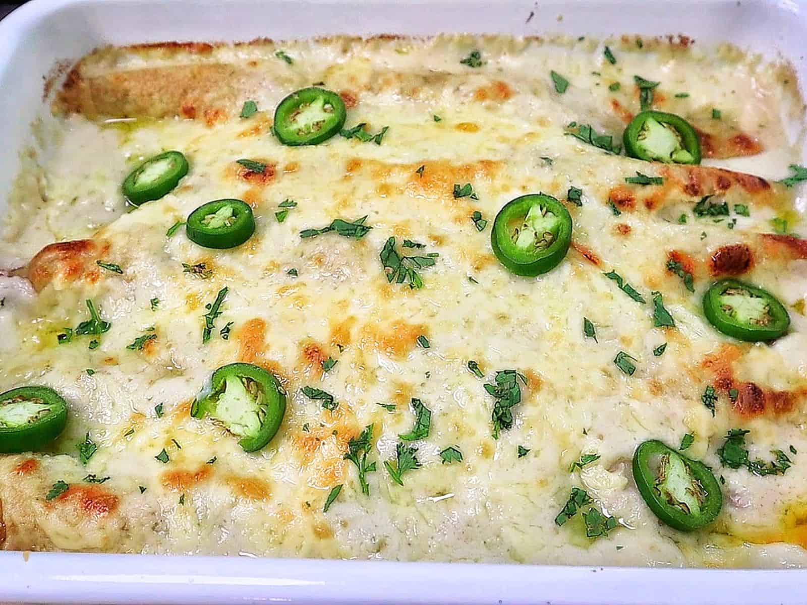 Creamy shrimp enchiladas baked, topped with melted Monterey Jack cheese, sliced jalapeños, and fresh cilantro covered in a rich salsa verde cream sauce.