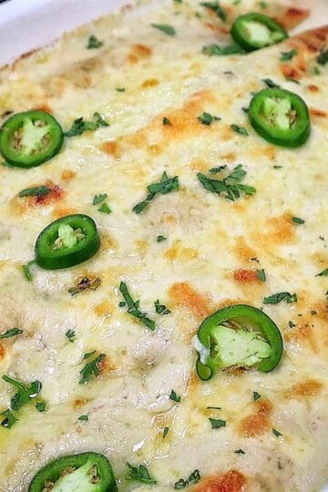 Creamy shrimp enchiladas baked, topped with melted Monterey Jack cheese, sliced jalapeños, and fresh cilantro covered in a rich salsa verde cream sauce.