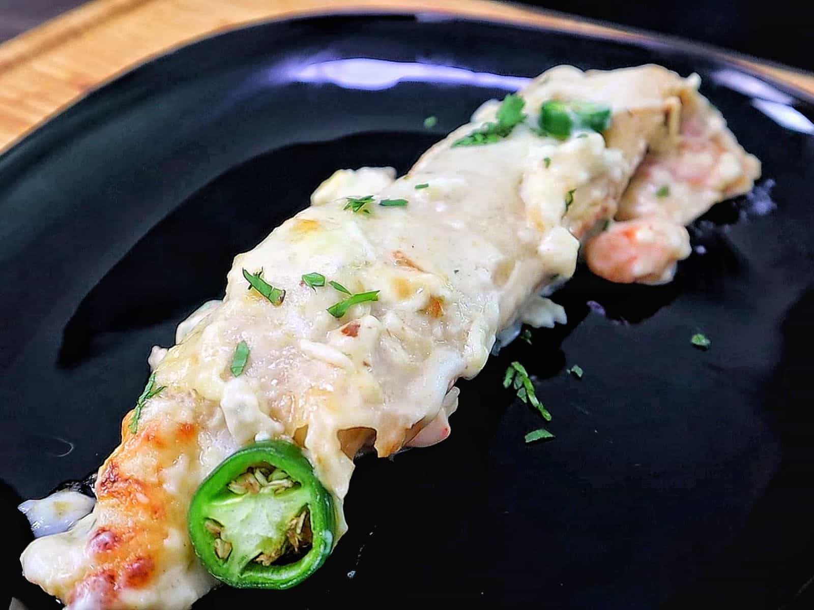 Creamy shrimp enchiladas baked, topped with melted Monterey Jack cheese, sliced jalapeños, and fresh cilantro covered in a rich salsa verde cream sauce.