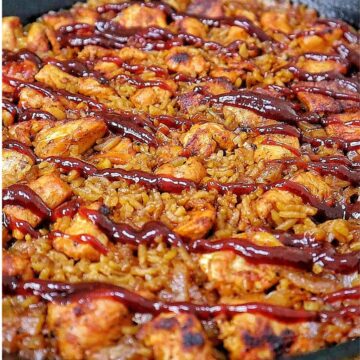 Honey BBQ chicken and rice cooked in a skillet, featuring tender chunks of seasoned chicken, fluffy rice, caramelized onions, and a glossy drizzle of rich barbecue sauce.