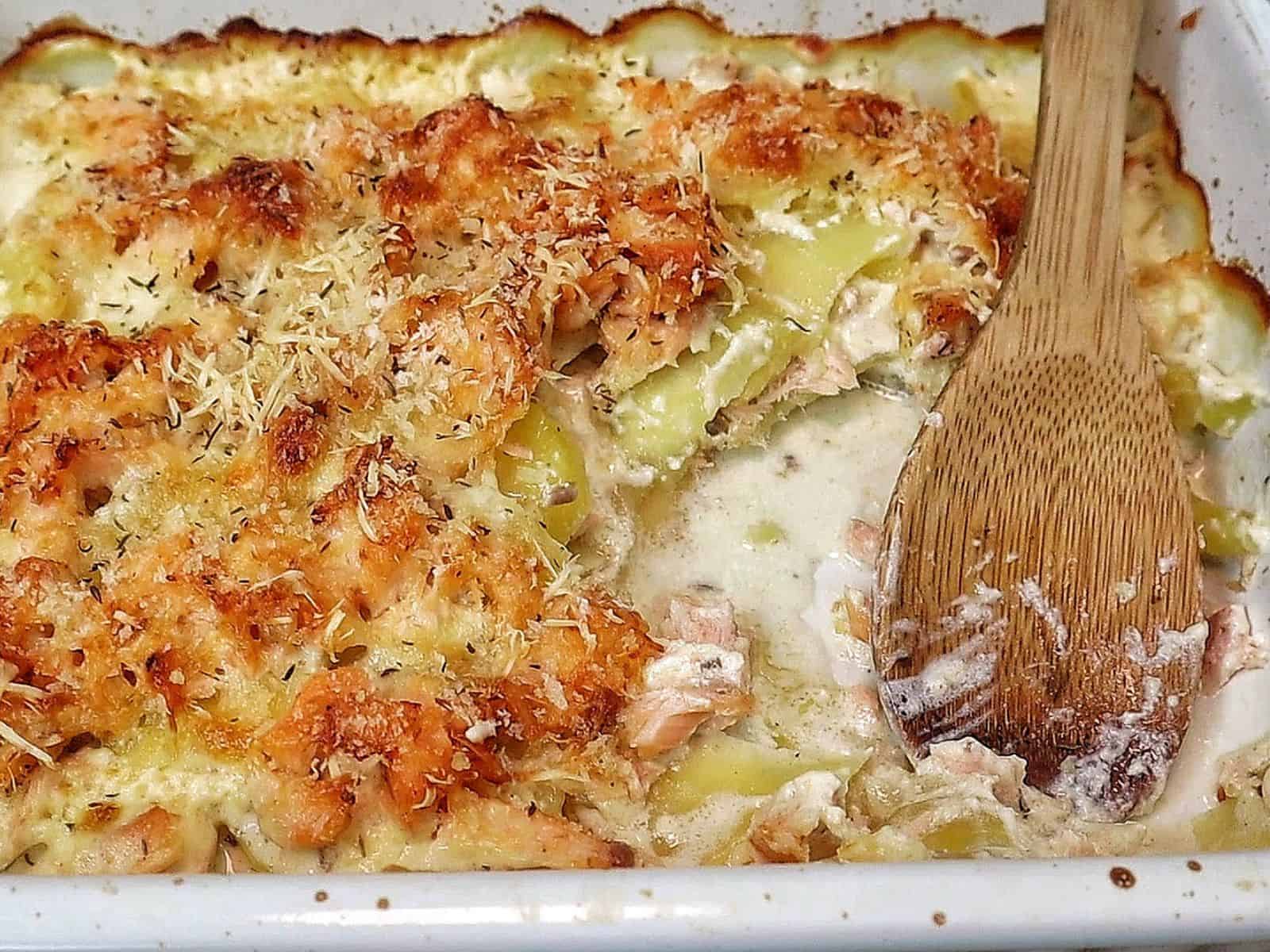 Golden brown salmon potato au gratin baked in a casserole dish with layers of tender sliced potatoes, flaky salmon, creamy parmesan sauce, and a crispy panko topping.