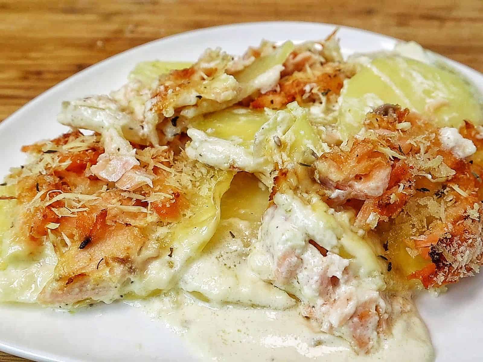 Golden brown salmon potato au gratin baked in a casserole dish with layers of tender sliced potatoes, flaky salmon, creamy parmesan sauce, and a crispy panko topping.