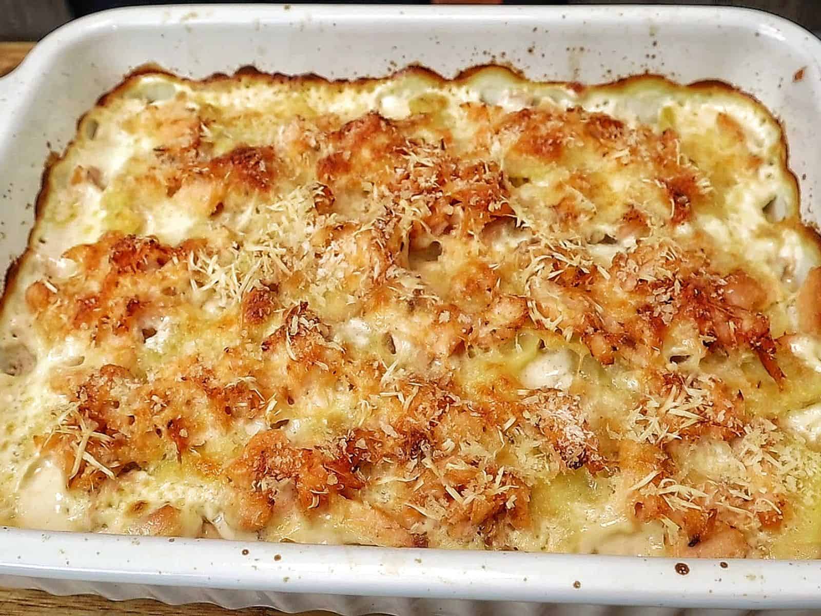 Golden brown salmon potato au gratin baked in a casserole dish with layers of tender sliced potatoes, flaky salmon, creamy parmesan sauce, and a crispy panko topping.
