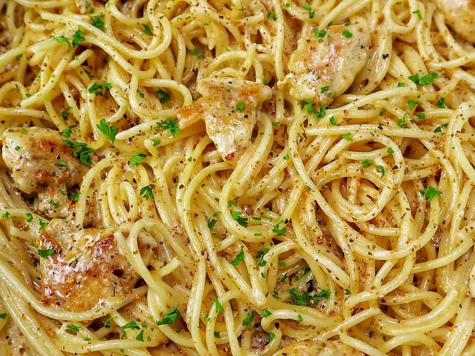 Three Cheese Chicken Spaghetti made with tender golden chicken breast, spaghetti coated in a rich Cajun garlic Parmesan cream sauce, and topped with fresh parsley.