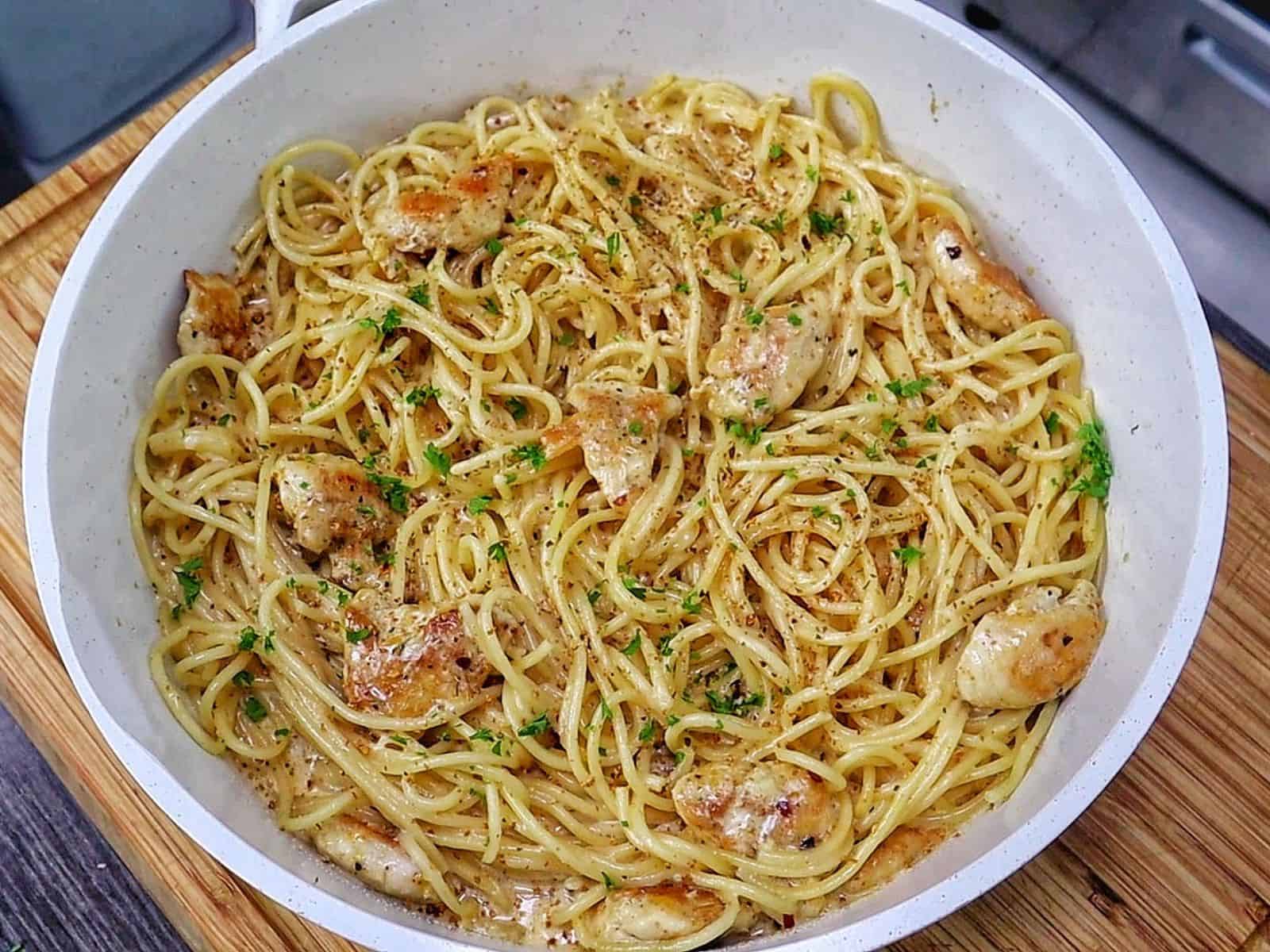 Three Cheese Chicken Spaghetti made with tender golden chicken breast, spaghetti coated in a rich Cajun garlic Parmesan cream sauce, and topped with fresh parsley.