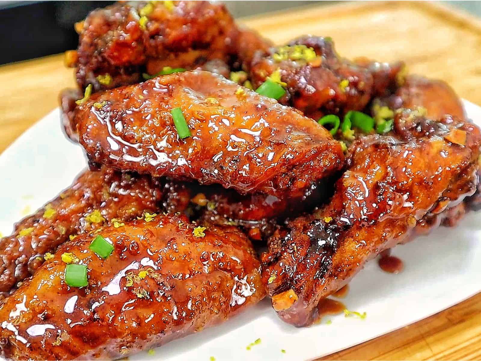 Crispy garlic soy chicken wings coated in a glossy sweet and savory soy garlic glaze, garnished with fresh green onions and lemon zest.