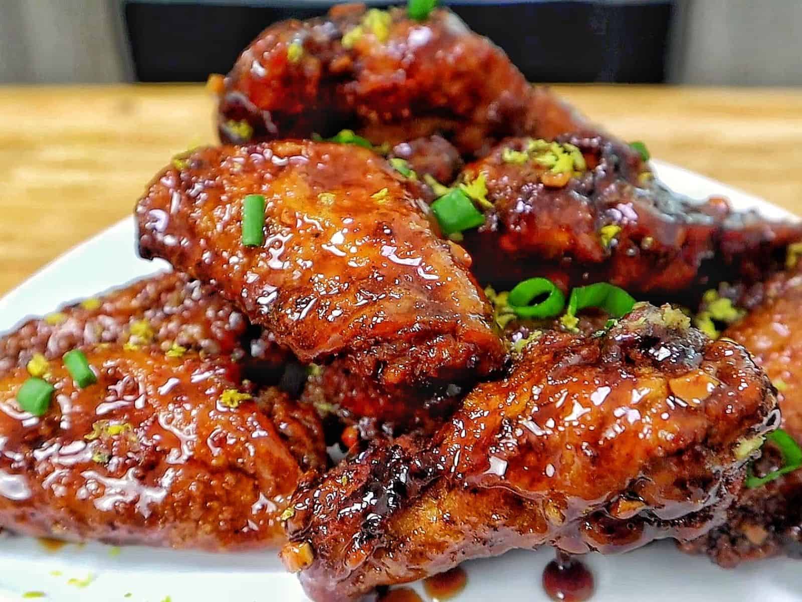 Crispy garlic soy chicken wings coated in a glossy sweet and savory soy garlic glaze, garnished with fresh green onions and lemon zest.