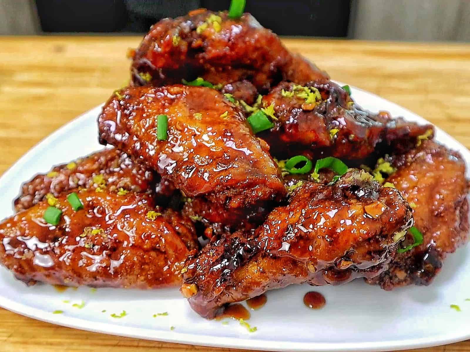 Crispy garlic soy chicken wings coated in a glossy sweet and savory soy garlic glaze, garnished with fresh green onions and lemon zest.