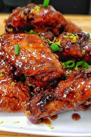 Crispy garlic soy chicken wings coated in a glossy sweet and savory soy garlic glaze, garnished with fresh green onions and lemon zest.