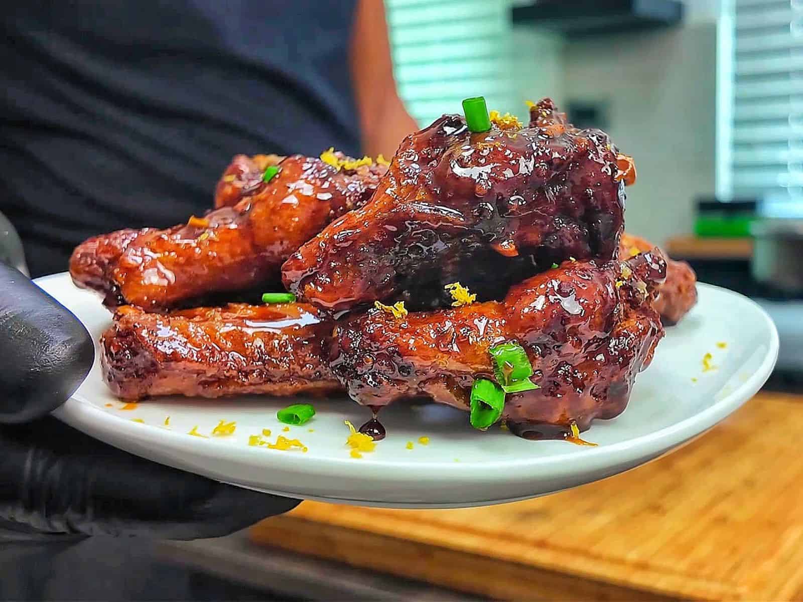 Crispy garlic soy chicken wings coated in a glossy sweet and savory soy garlic glaze, garnished with fresh green onions and lemon zest.