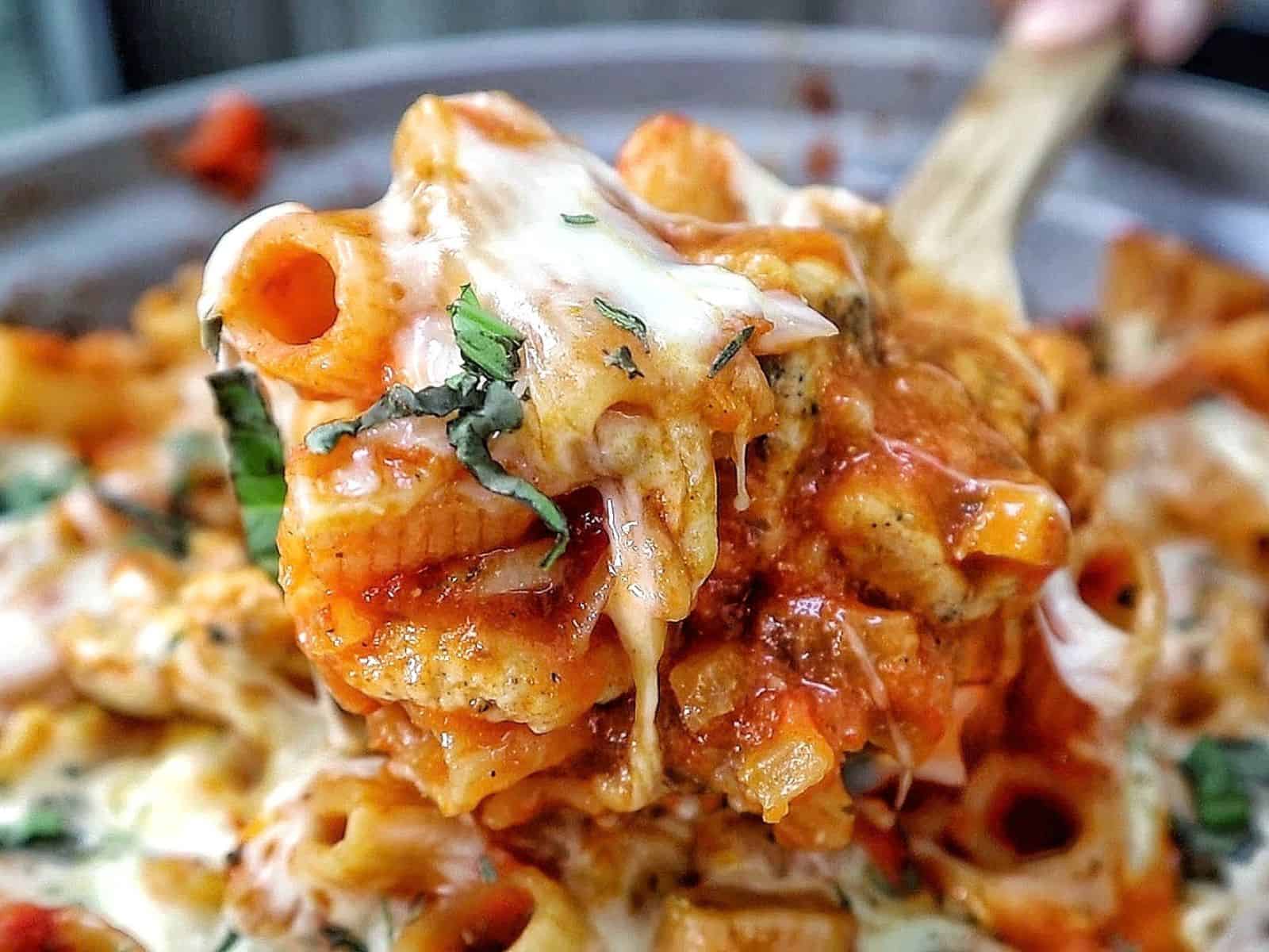 Cheesy Chicken Parmesan Pasta made with rigatoni, seasoned chicken, marinara sauce, melted mozzarella and Parmesan cheese, finished with fresh basil and Italian herbs.
