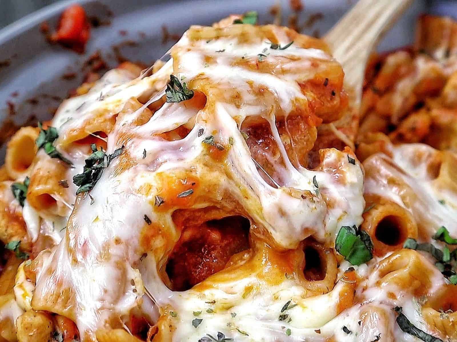 Cheesy Chicken Parmesan Pasta made with rigatoni, seasoned chicken, marinara sauce, melted mozzarella and Parmesan cheese, finished with fresh basil and Italian herbs.