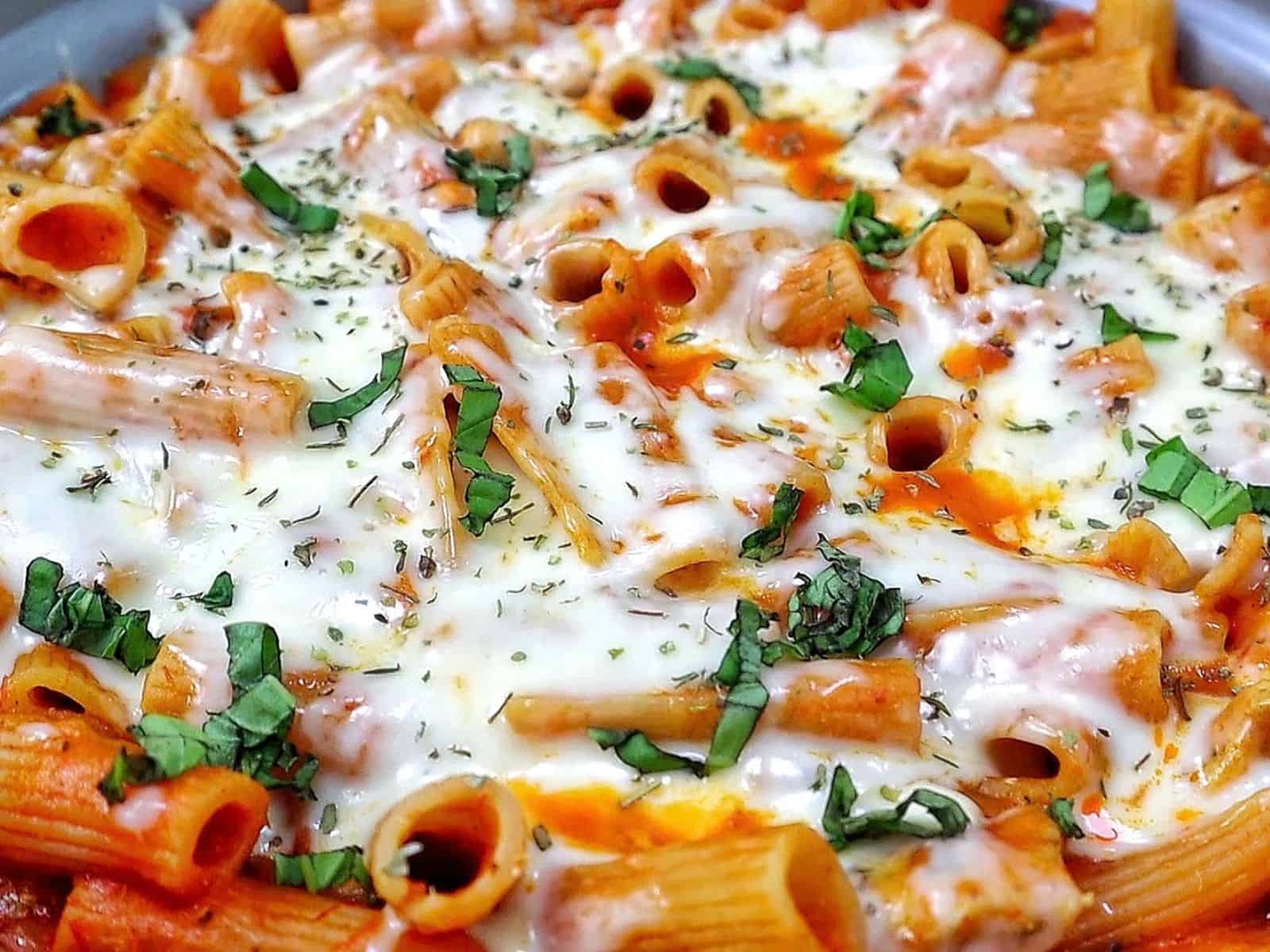 Cheesy Chicken Parmesan Pasta made with rigatoni, seasoned chicken, marinara sauce, melted mozzarella and Parmesan cheese, finished with fresh basil and Italian herbs.