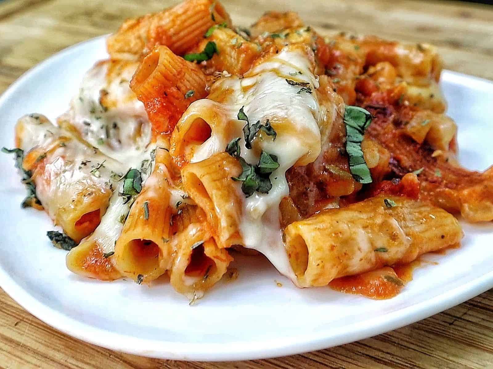 Cheesy Chicken Parmesan Pasta made with rigatoni, seasoned chicken, marinara sauce, melted mozzarella and Parmesan cheese, finished with fresh basil and Italian herbs.
