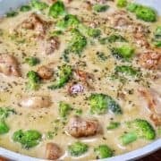 Tender seasoned chicken and fresh broccoli florets coated in a rich, creamy three-cheese garlic sauce in a skillet