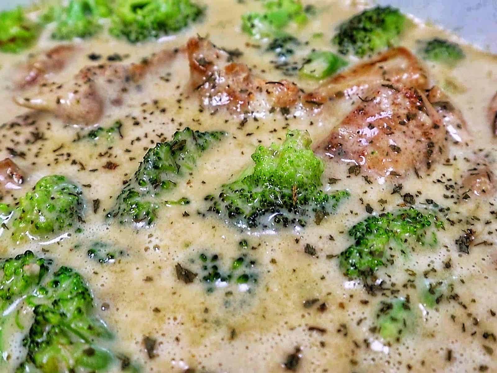 Tender seasoned chicken and fresh broccoli florets coated in a rich, creamy three-cheese garlic sauce in a skillet