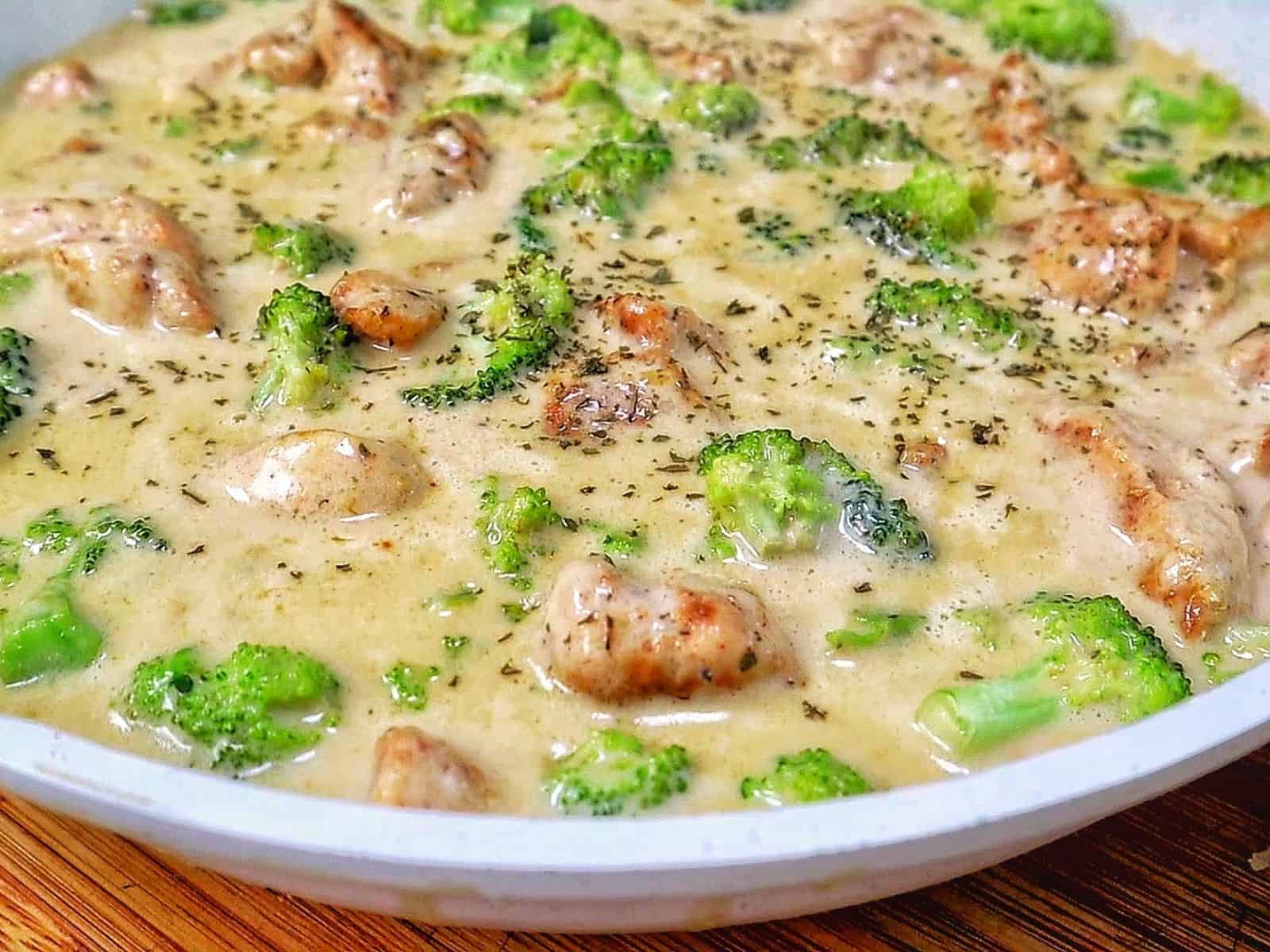 Tender seasoned chicken and fresh broccoli florets coated in a rich, creamy three-cheese garlic sauce in a skillet