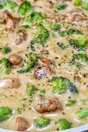 Tender seasoned chicken and fresh broccoli florets coated in a rich, creamy three-cheese garlic sauce in a skillet
