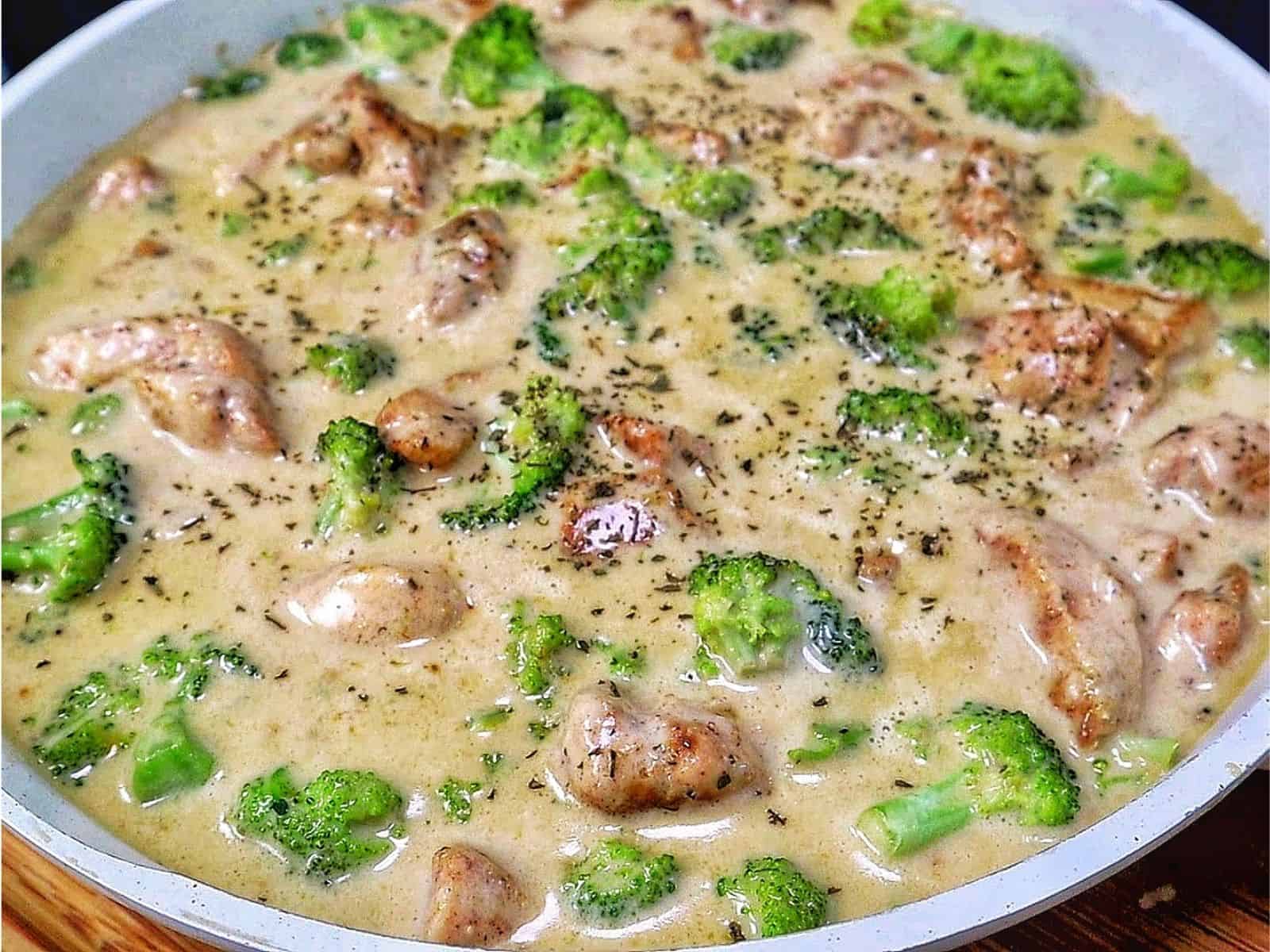 Tender seasoned chicken and fresh broccoli florets coated in a rich, creamy three-cheese garlic sauce in a skillet