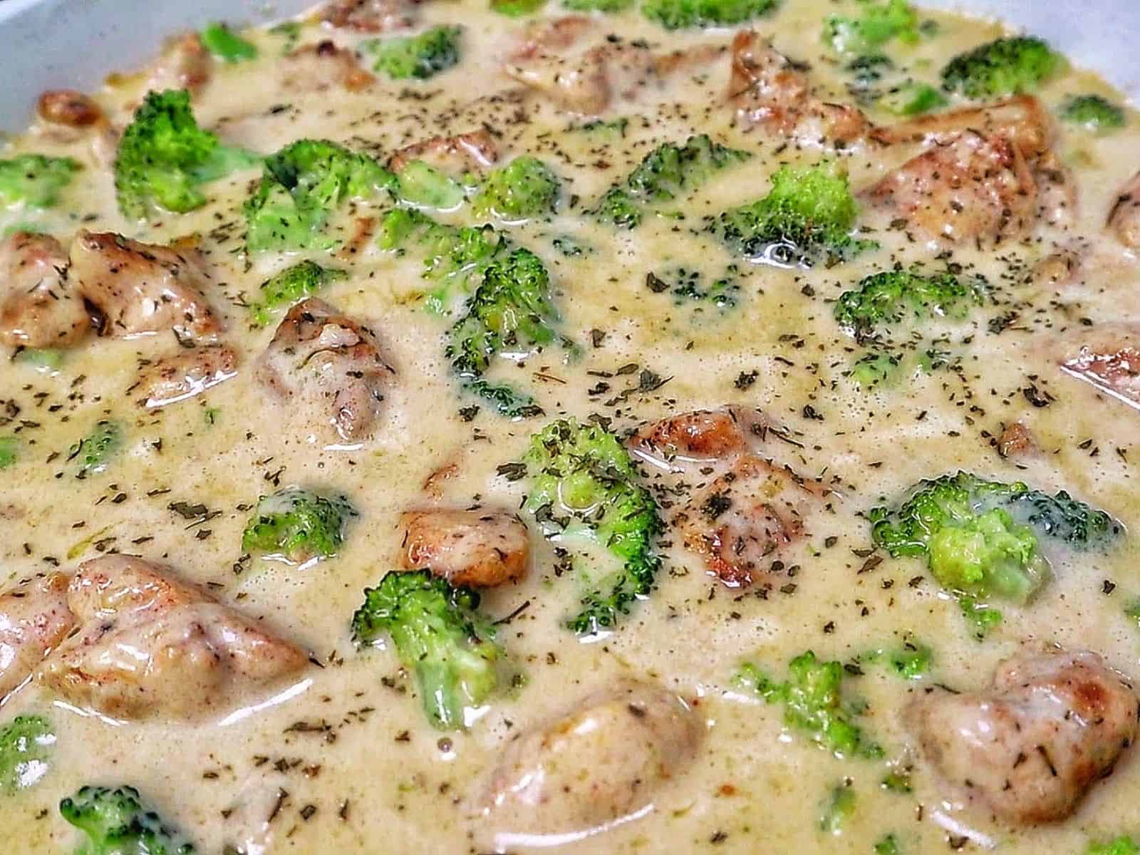 Tender seasoned chicken and fresh broccoli florets coated in a rich, creamy three-cheese garlic sauce in a skillet