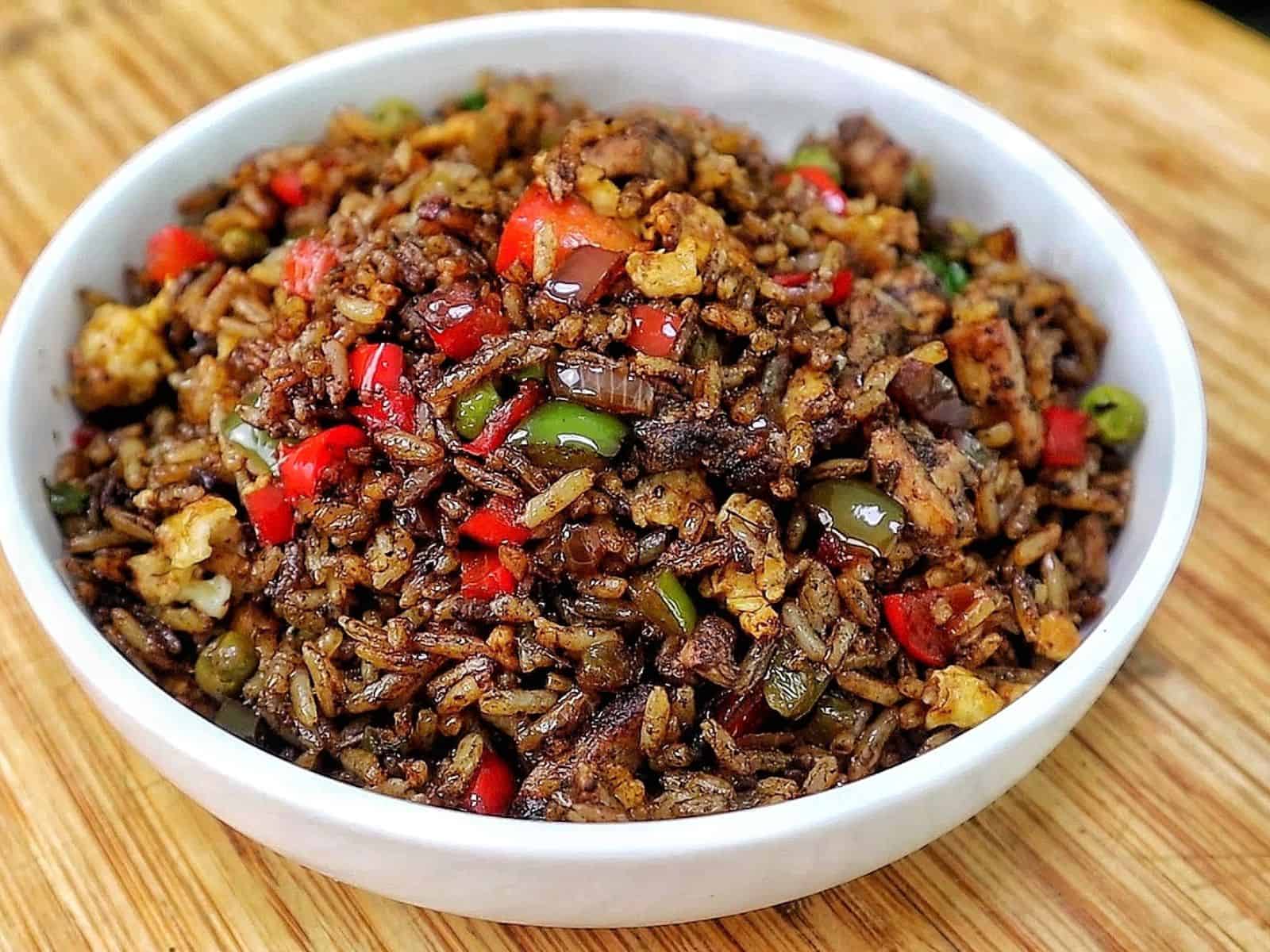 Homemade Jerk Chicken Fried Rice loaded with seasoned chicken thighs, fluffy rice, scrambled eggs, red and green bell peppers, peas and green onions in a savory jerk and soy sauce seasoning.