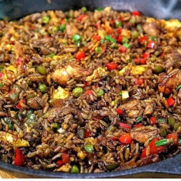 Homemade Jerk Chicken Fried Rice loaded with seasoned chicken thighs, fluffy rice, scrambled eggs, red and green bell peppers, peas and green onions in a savory jerk and soy sauce seasoning.