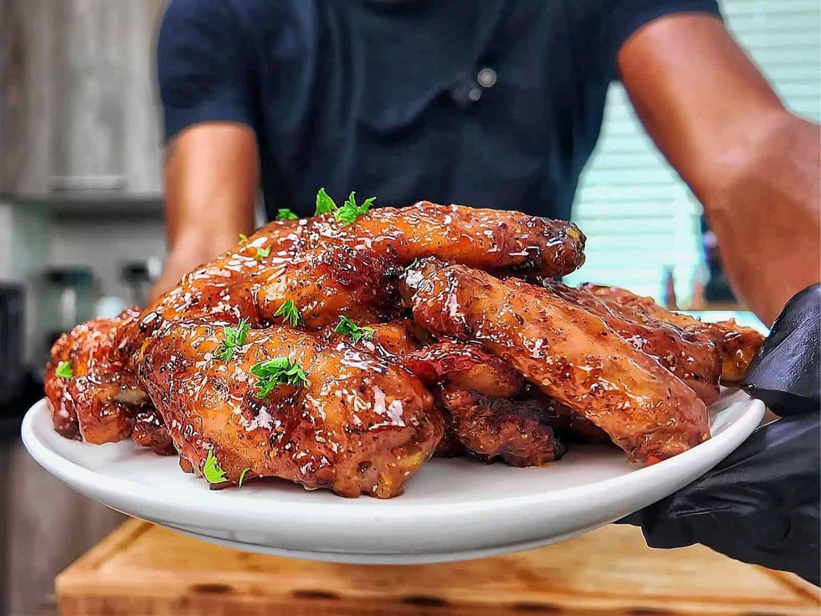Crispy baked lemon pepper chicken wings coated in a sticky honey lemon glaze and garnished with fresh chopped parsley.