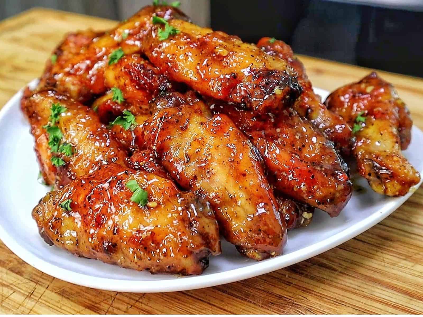Crispy baked lemon pepper chicken wings coated in a sticky honey lemon glaze and garnished with fresh chopped parsley.