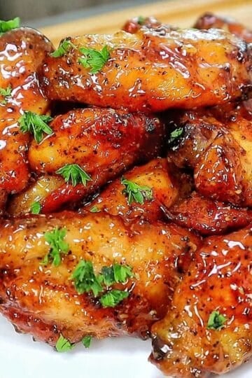 Crispy baked lemon pepper chicken wings coated in a sticky honey lemon glaze and garnished with fresh chopped parsley.