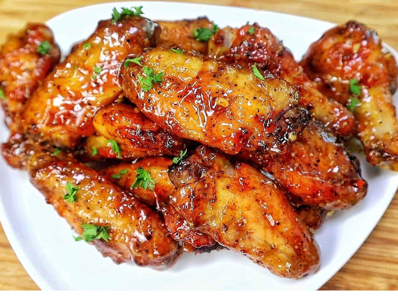 Crispy baked lemon pepper chicken wings coated in a sticky honey lemon glaze and garnished with fresh chopped parsley.