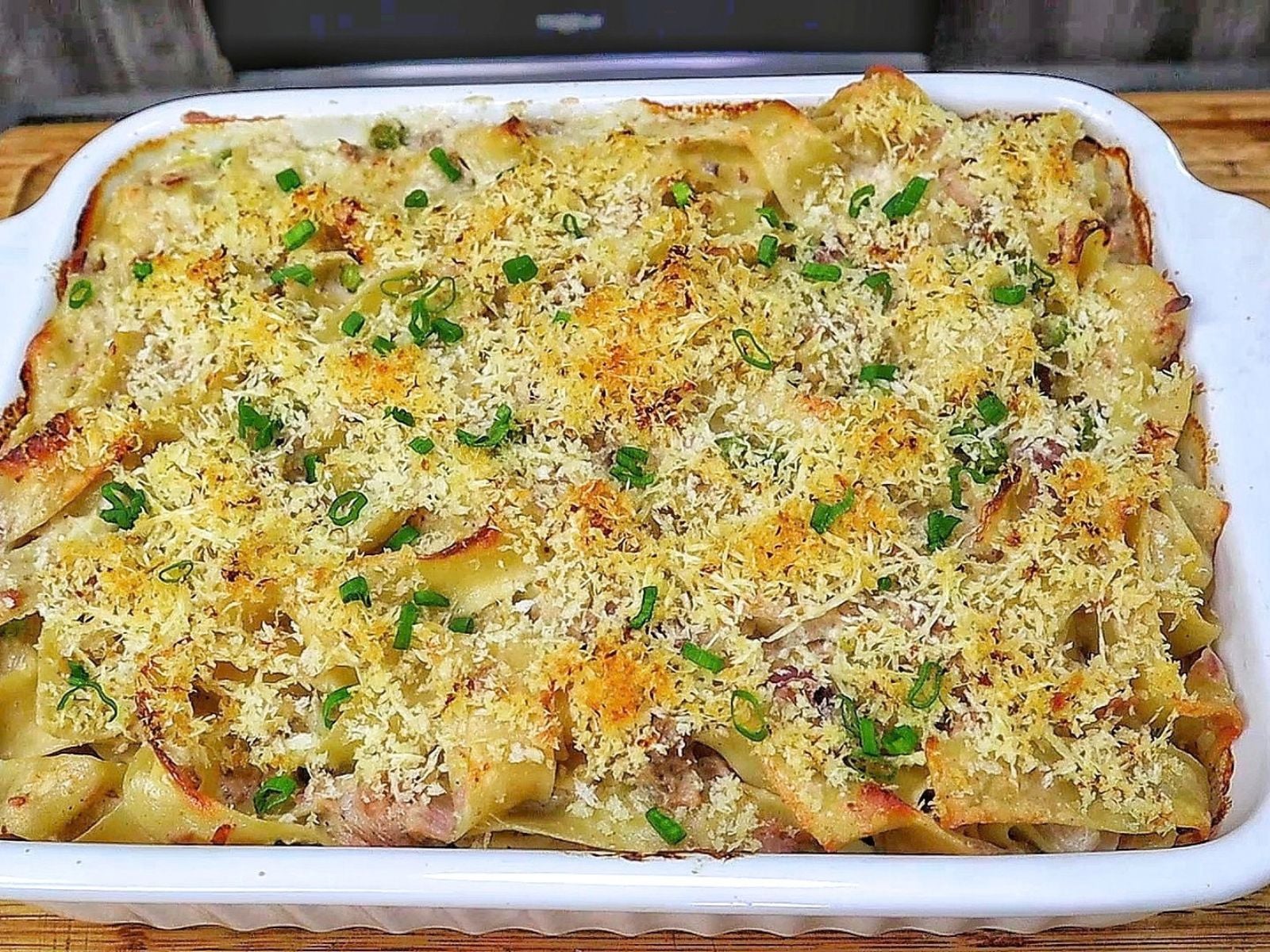 Homemade tuna noodle casserole made with wide egg noodles, tuna, peas and a creamy white cheddar sauce, topped with crispy golden Parmesan Panko breadcrumbs and fresh chopped chives.
