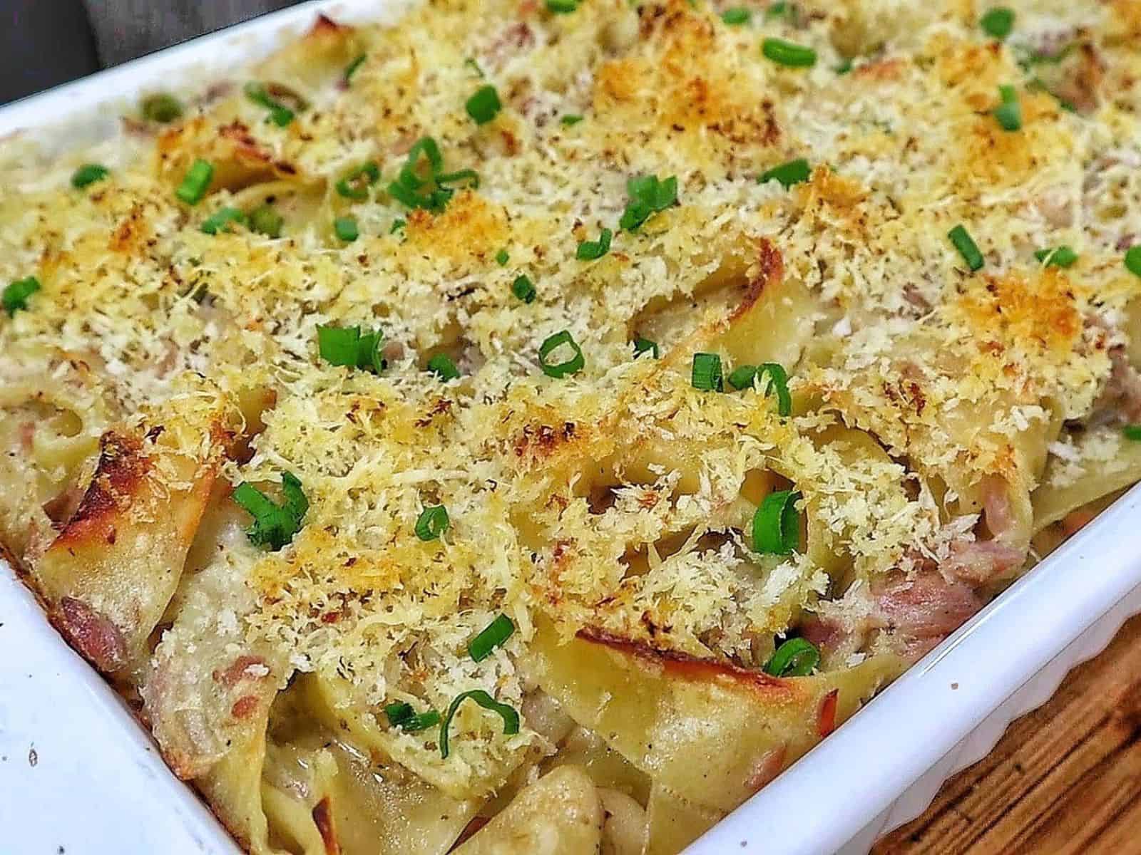 Homemade tuna noodle casserole made with wide egg noodles, tuna, peas and a creamy white cheddar sauce, topped with crispy golden Parmesan Panko breadcrumbs and fresh chopped chives.