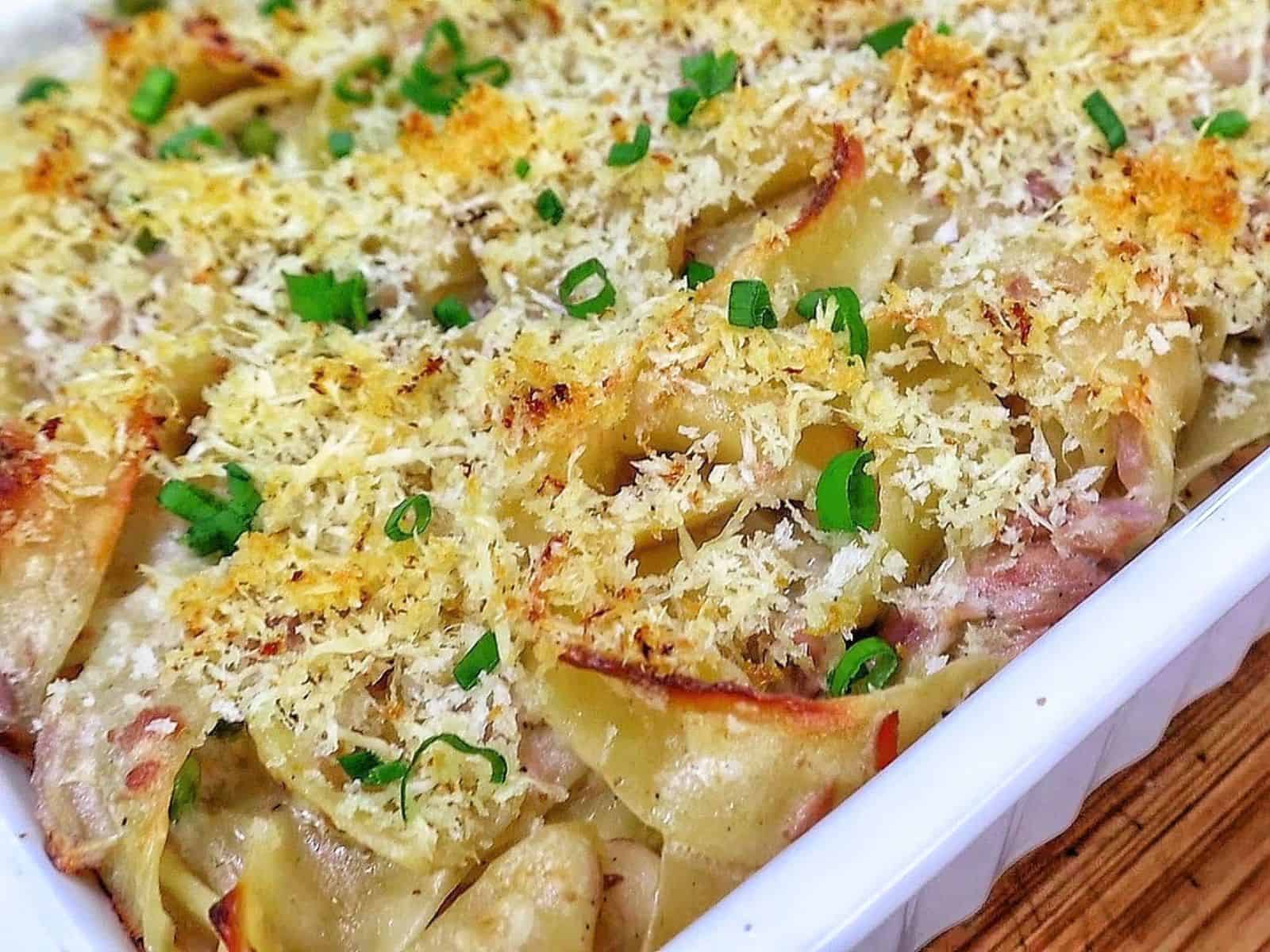 Homemade tuna noodle casserole made with wide egg noodles, tuna, peas and a creamy white cheddar sauce, topped with crispy golden Parmesan Panko breadcrumbs and fresh chopped chives.