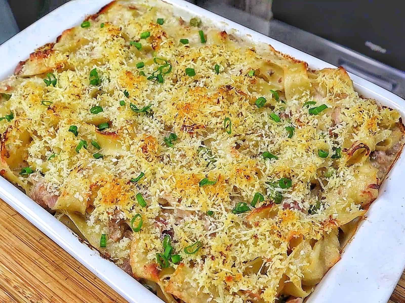 Homemade tuna noodle casserole made with wide egg noodles, tuna, peas and a creamy white cheddar sauce, topped with crispy golden Parmesan Panko breadcrumbs and fresh chopped chives.