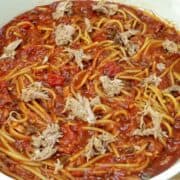 Close-up of BBQ Pulled Pork Spaghetti featuring shredded pork, spaghetti noodles, diced tomatoes, and a thick, smoky barbecue tomato sauce.