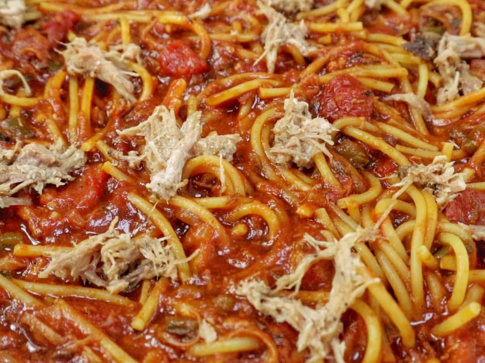 Close-up of BBQ Pulled Pork Spaghetti featuring shredded pork, spaghetti noodles, diced tomatoes, and a thick, smoky barbecue tomato sauce.