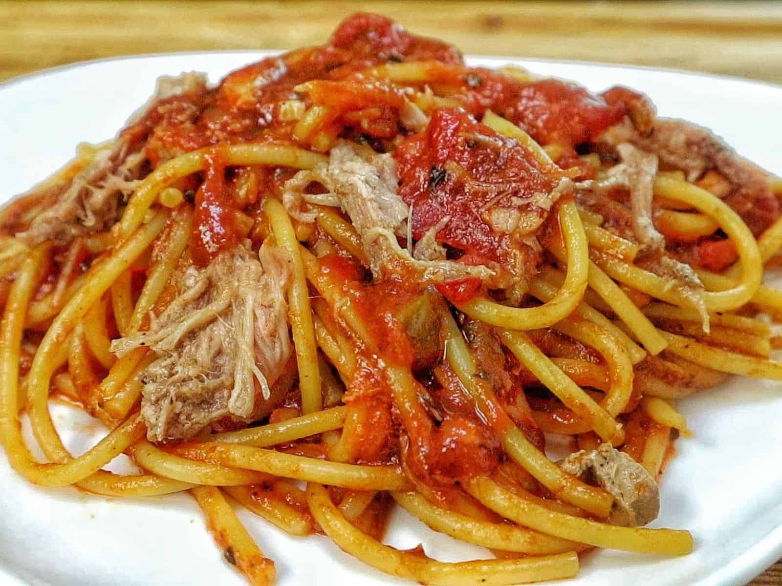 Close-up of BBQ Pulled Pork Spaghetti featuring shredded pork, spaghetti noodles, diced tomatoes, and a thick, smoky barbecue tomato sauce.