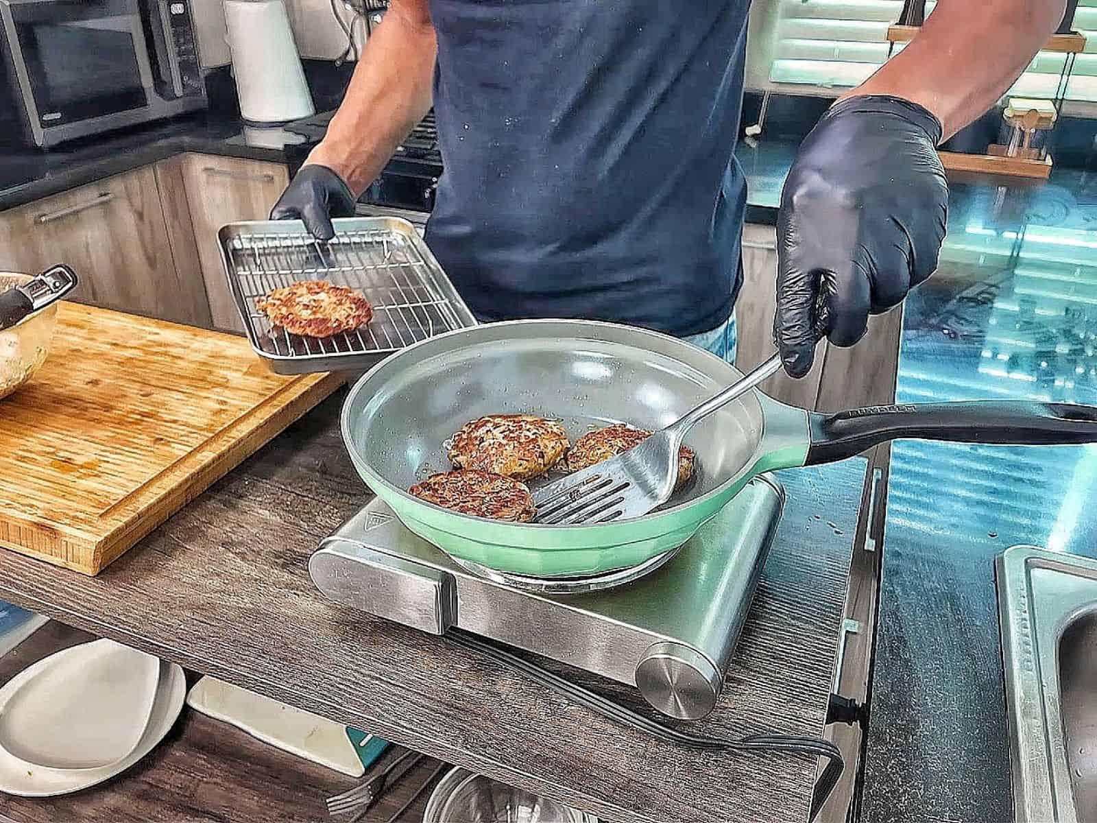 Crispy homemade tuna patties pan-fried until golden brown with chopped onions and herbs, stacked on a white plate.