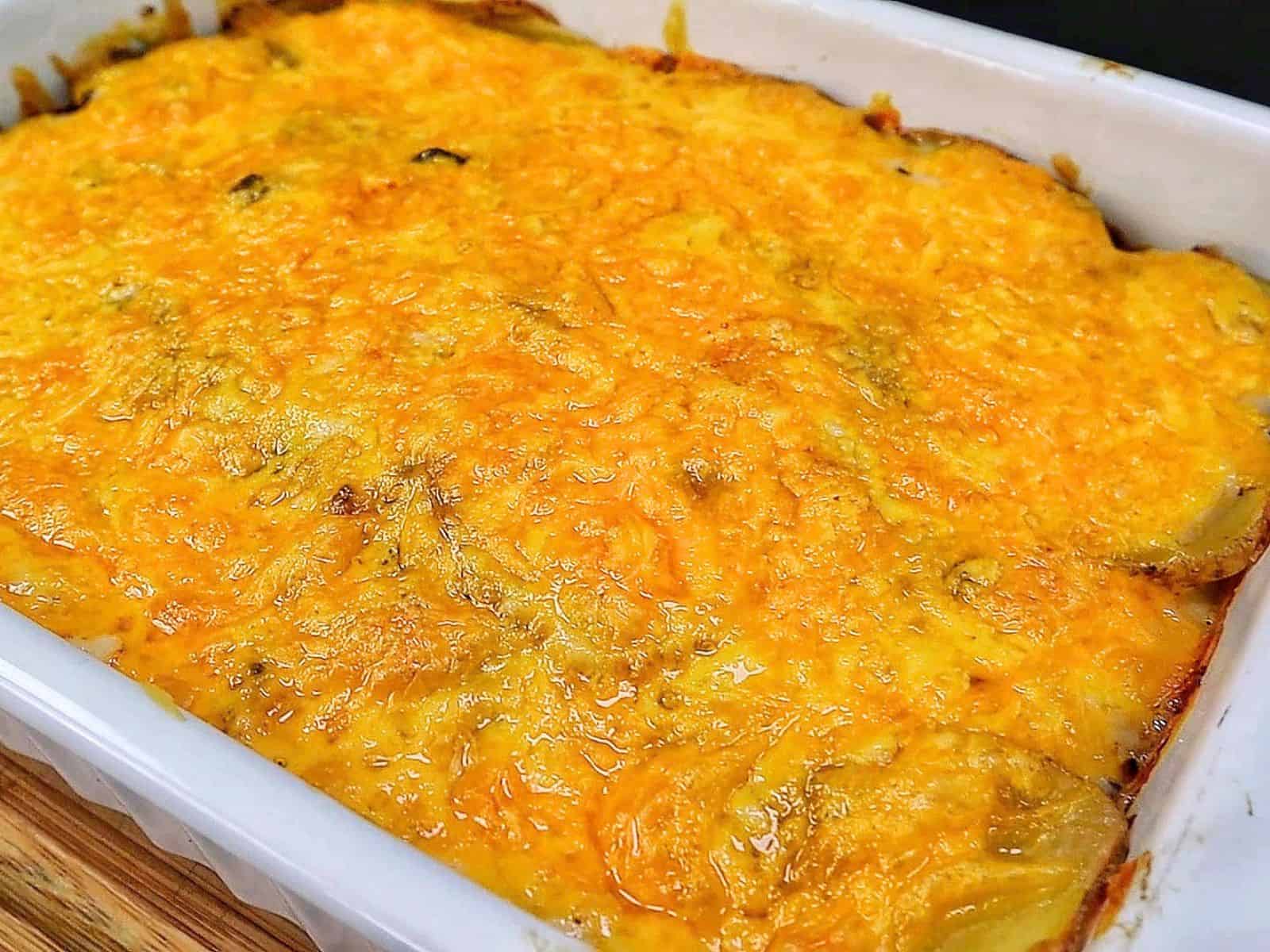 Homemade hamburger potato casserole layered with seasoned ground beef, tender sliced potatoes, creamy mushroom sauce and melted golden cheddar cheese in a white baking dish.