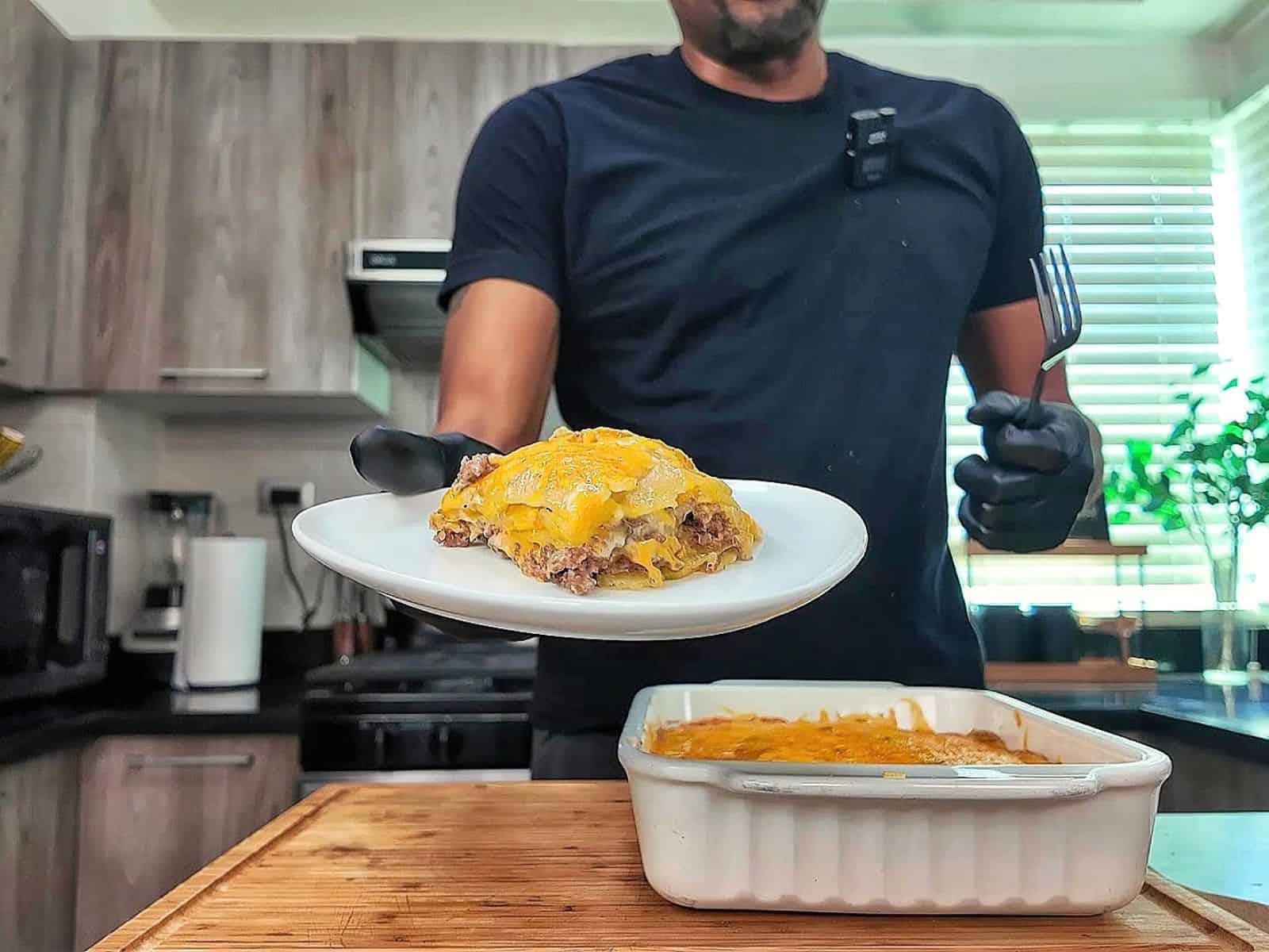 Homemade hamburger potato casserole layered with seasoned ground beef, tender sliced potatoes, creamy mushroom sauce and melted golden cheddar cheese in a white baking dish.