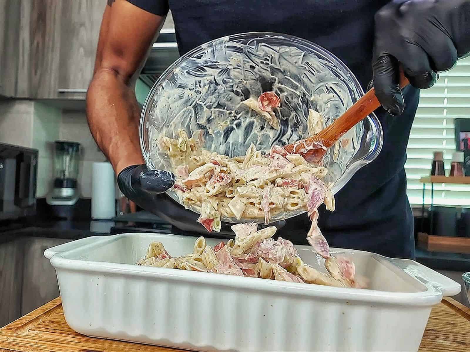Homemade Italian Grinder Pasta Bake in a white casserole dish, topped with bubbly golden-brown melted cheese and sprinkled with Italian herbs.