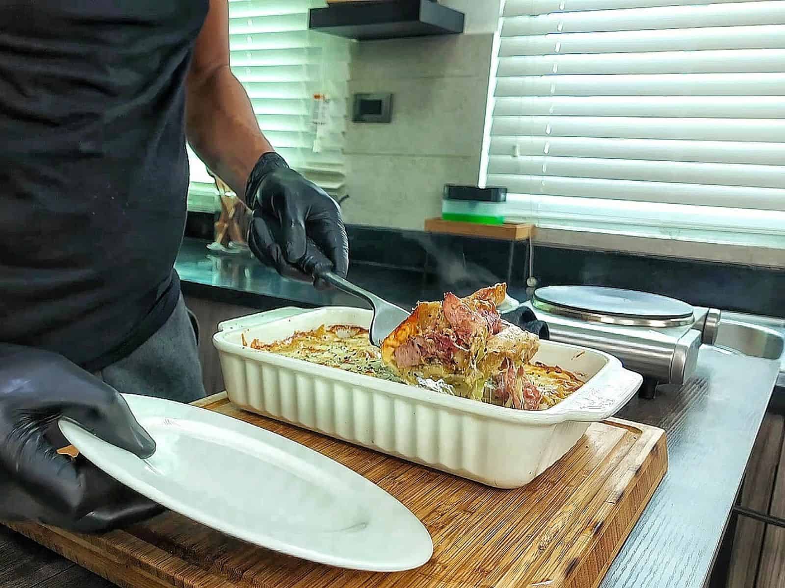 Homemade Italian Grinder Pasta Bake in a white casserole dish, topped with bubbly golden-brown melted cheese and sprinkled with Italian herbs.