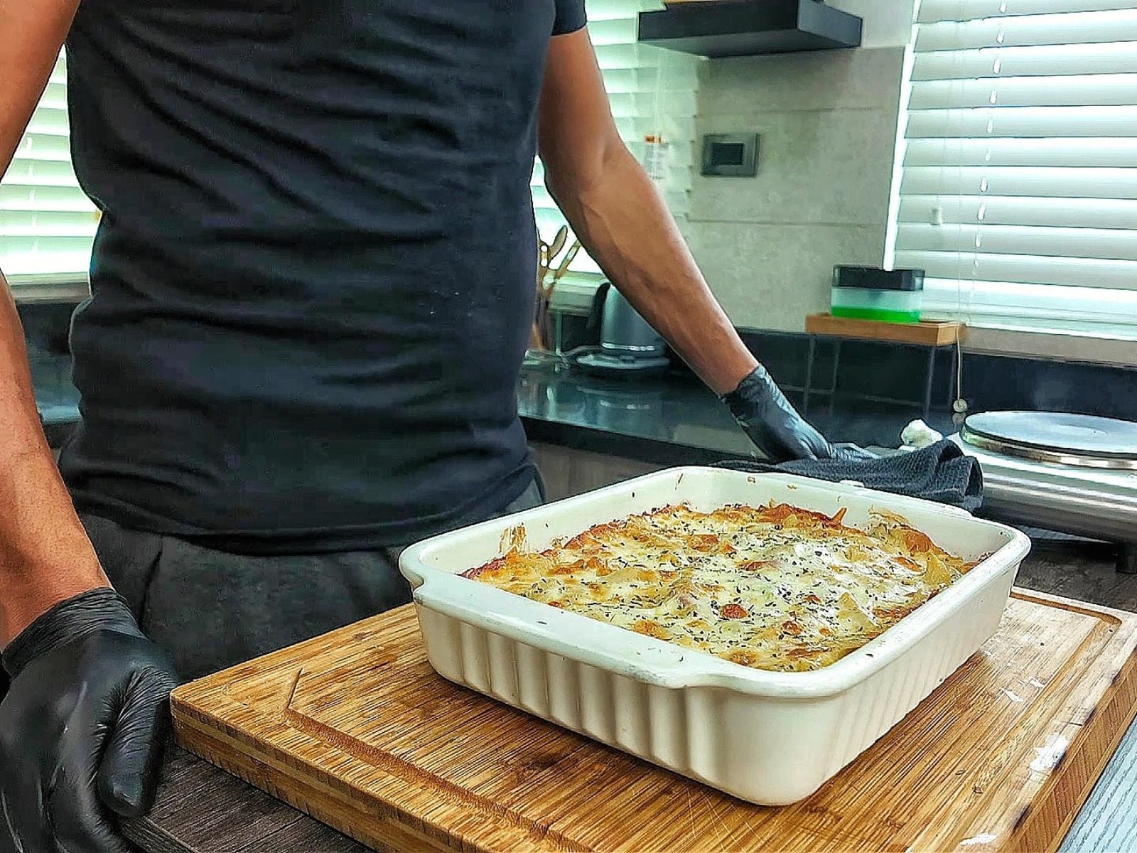 Homemade Italian Grinder Pasta Bake in a white casserole dish, topped with bubbly golden-brown melted cheese and sprinkled with Italian herbs.