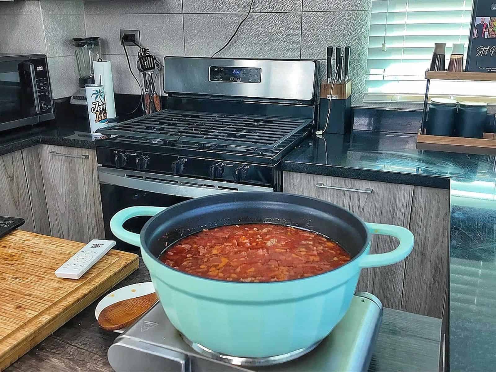 Homemade Meat Lovers Pizza Soup in a white bowl, loaded with Italian sausage, pepperoni, bacon, rich tomato broth, and shredded mozzarella and Parmesan cheese.