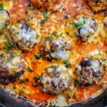 Juicy Tex-Mex meatballs topped with melted Mexican cheese in a smoky chipotle tomato sauce, garnished with fresh parsley in a cast-iron skillet.